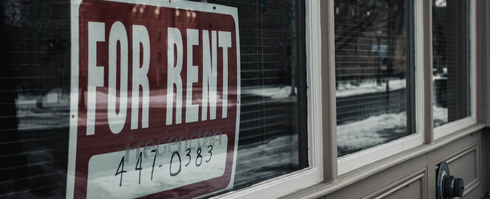 For Rent sign on window of vacant property, urban street view in winter, seeking tenants for commercial space