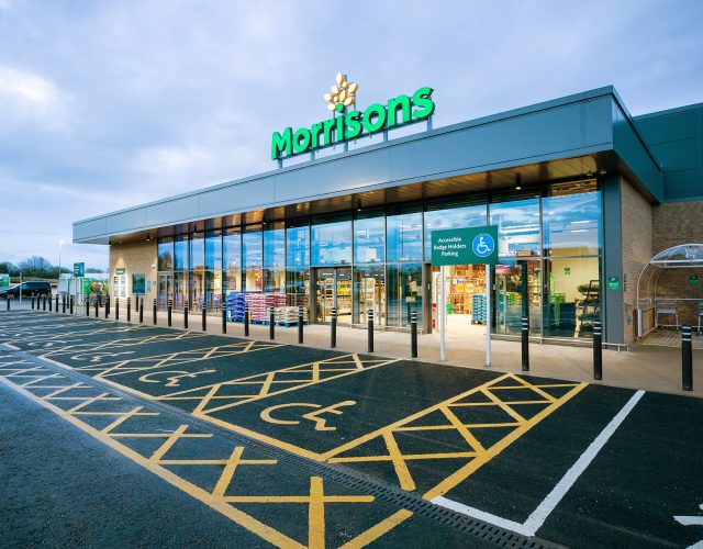 Exterior view of supermarket with accessible parking spots and automatic entrance doors.